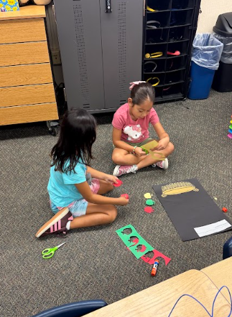 students cutting paper apples working on a math poster
