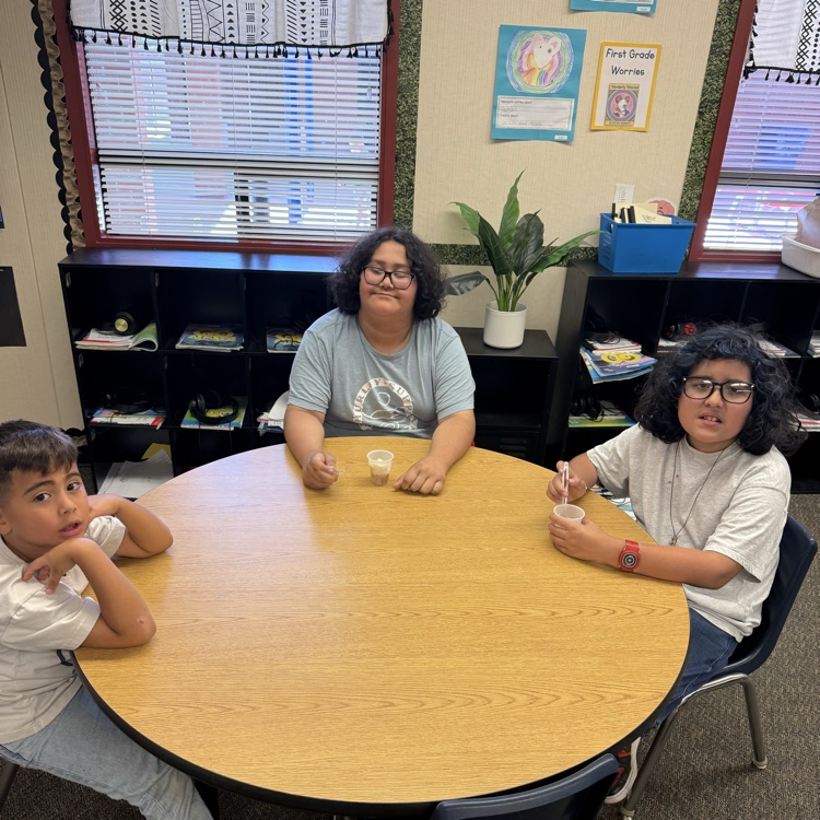 three kids smiling at a table