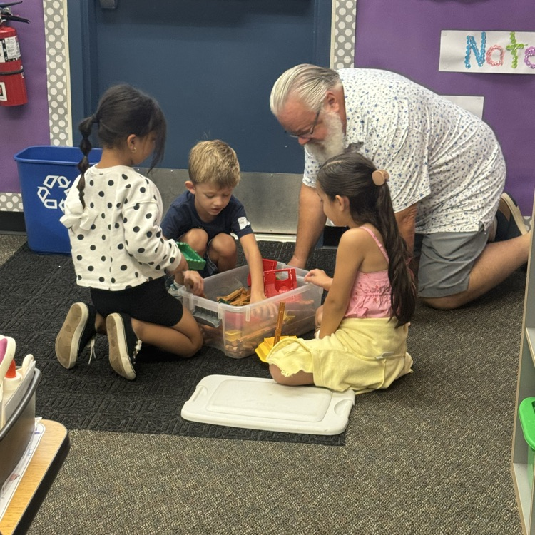 man playing with blocks with students