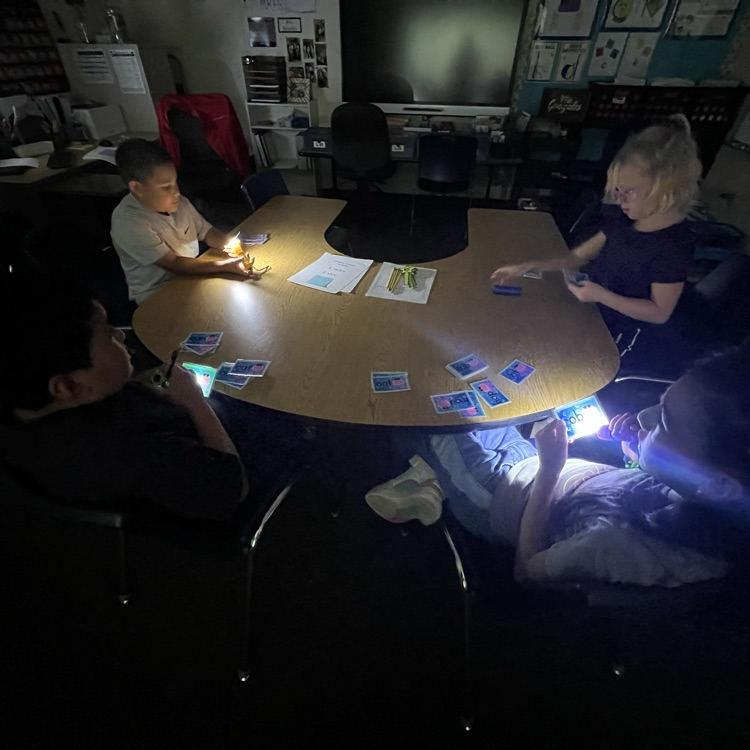 students reading words in the dark with flashlights