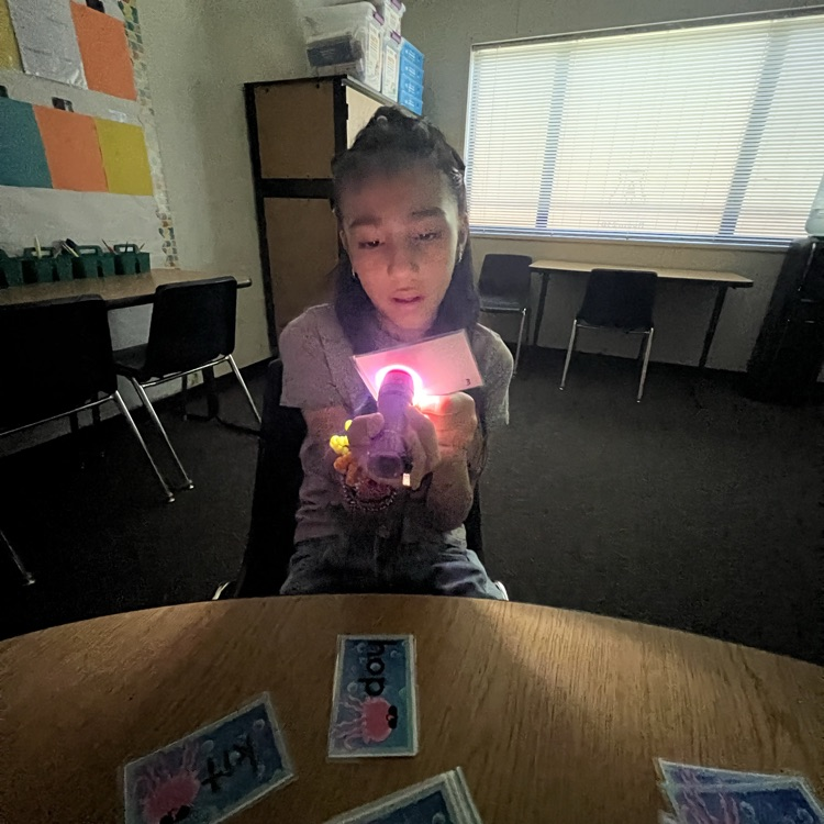 girl using a flashlight to read a word card