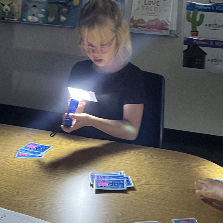girl looking at a flash card with a flashlight behind the card