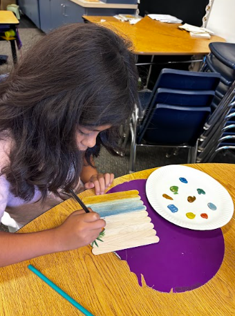 student painting popsicle sticks