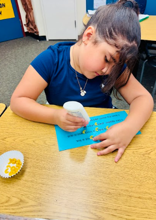 student gluing pasta in a sentence representing a comma