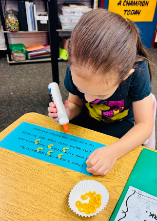 student gluing pasta in a sentence representing a comma