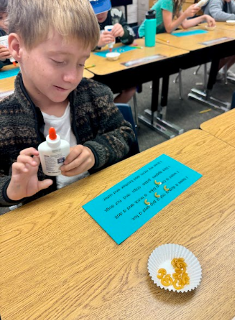student gluing pasta in a sentence representing a comma