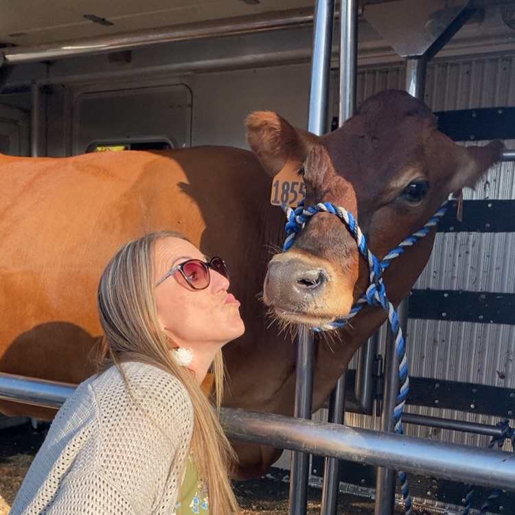 lady pretending to kiss a brown cow