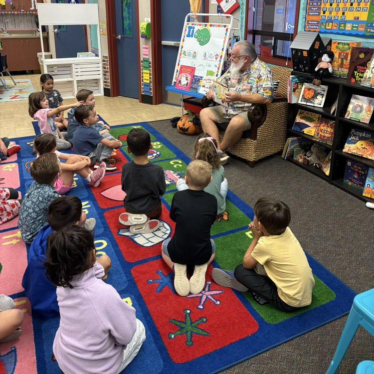 man reading a book to students 