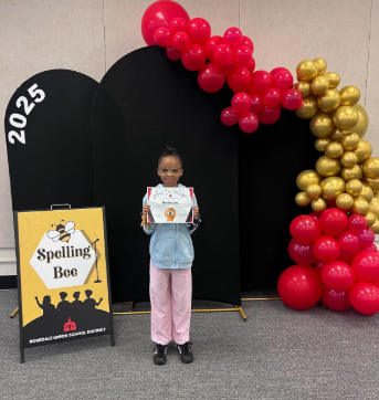 student with certificate in front of balloons