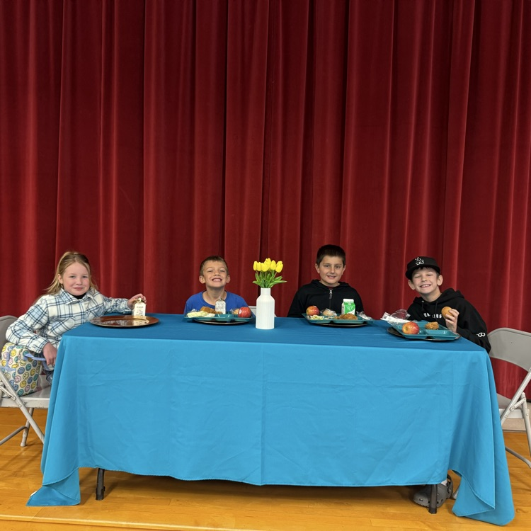 students eating lunch at a table decorated with a nice tablecloth and flowers