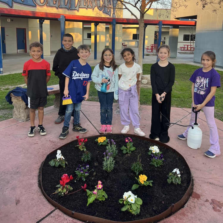 kids standing around a planter of flowers