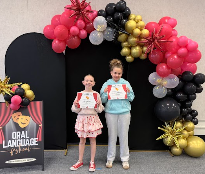 students with certificates in front of balloons 