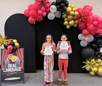 students with certificates in front of balloons 