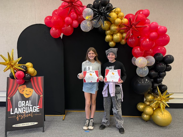 students with certificates in front of balloons 