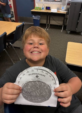 student holding a paper constellation viewer