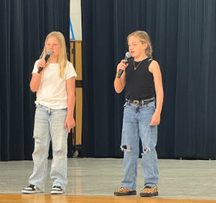 students singing on stage with a microphone