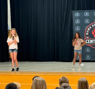 students singing on stage with a microphone