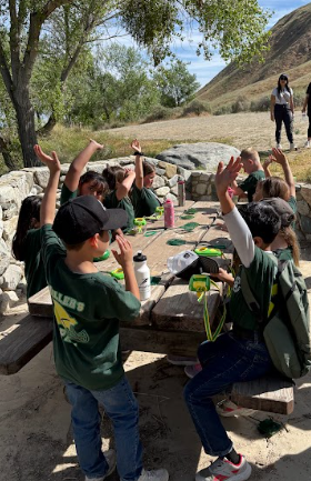 students raising hands at a table
