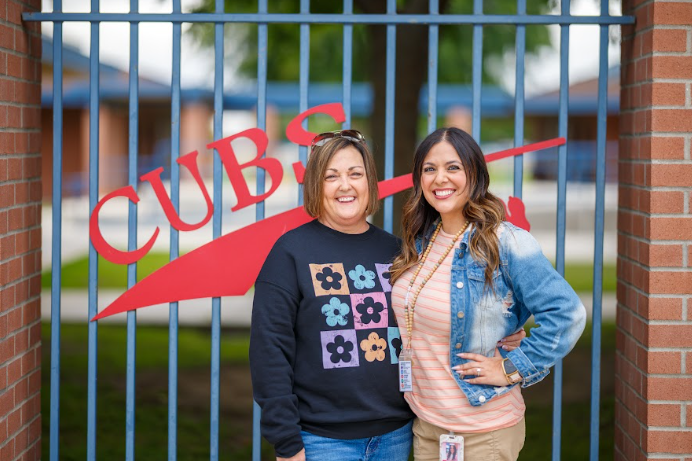 two ladies in front of a Cubs sign