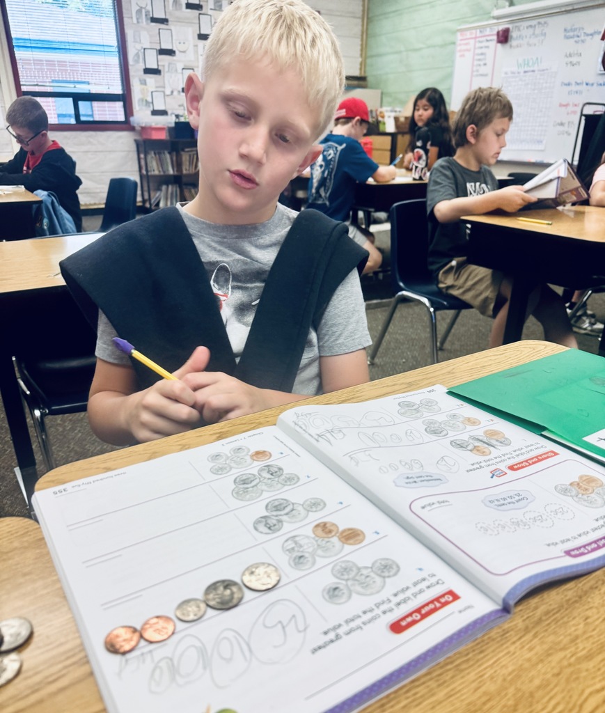 student using coins to solve problems in math book
