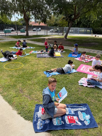 students reading books laying on beach towels
