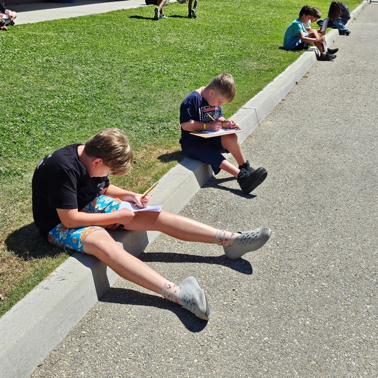boys sitting on the curb working on an assignment