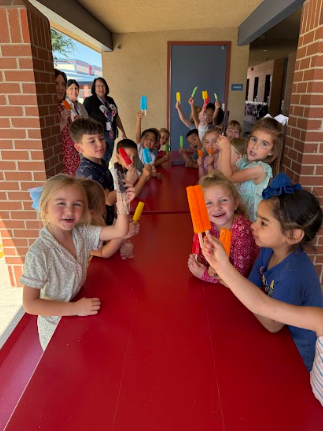 students eating popsicles sitting at a table