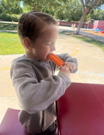 student eating a popsicle at a table