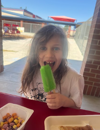 student eating a popsicle at a table