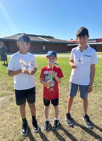 students holding a butterfly puppet