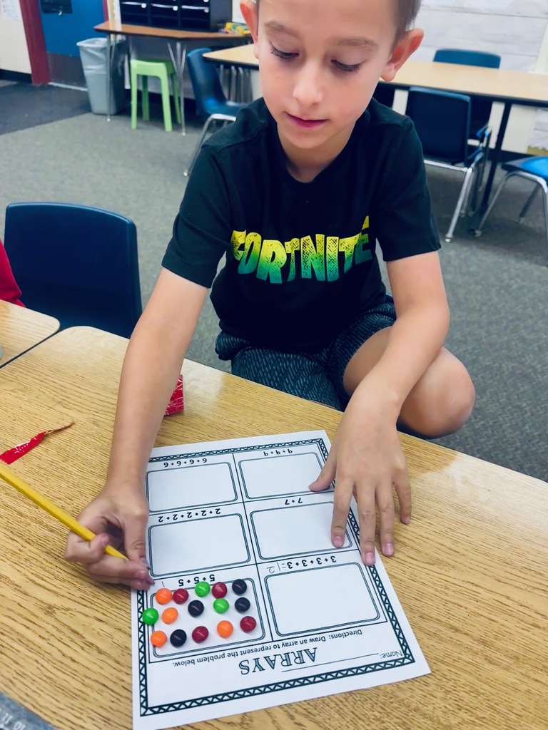 student at desk working with skittles and math arrays