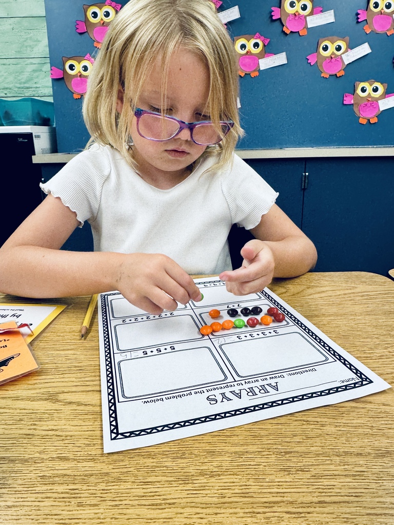 student at desk working with skittles and math arrays