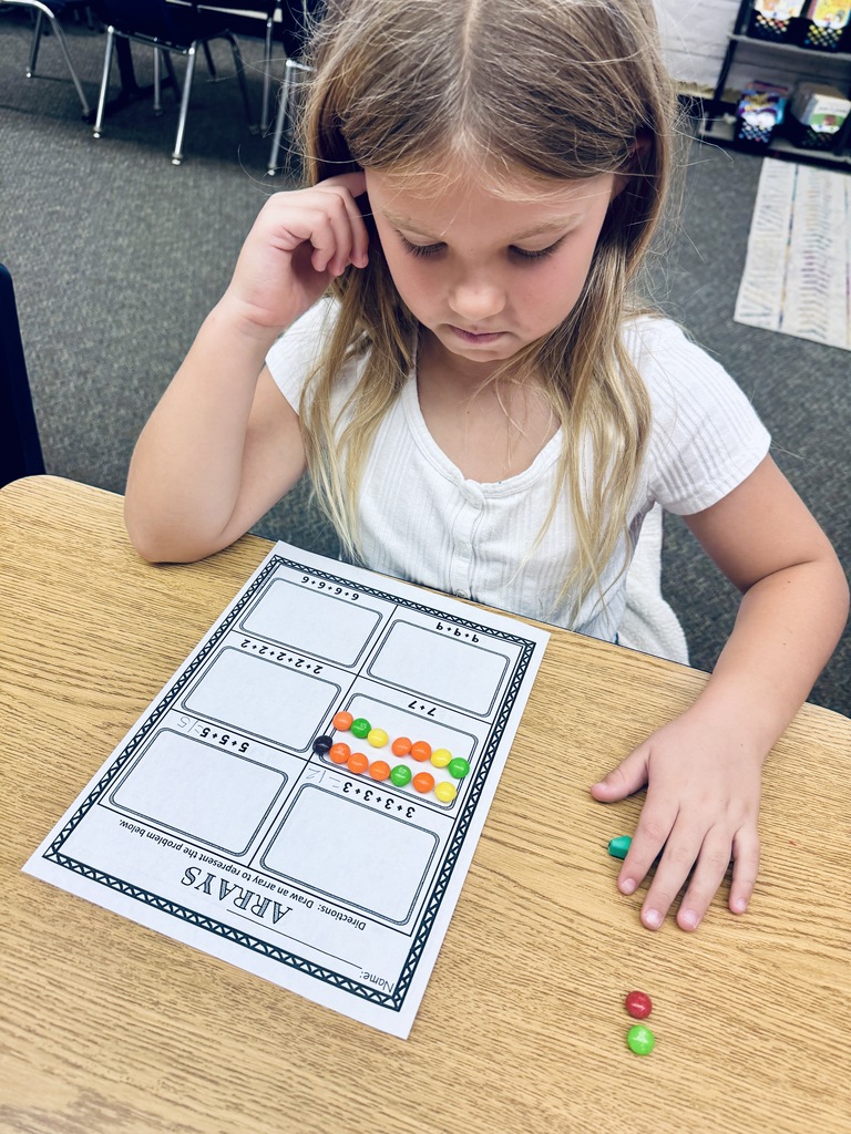 student at desk working with skittles and math arrays
