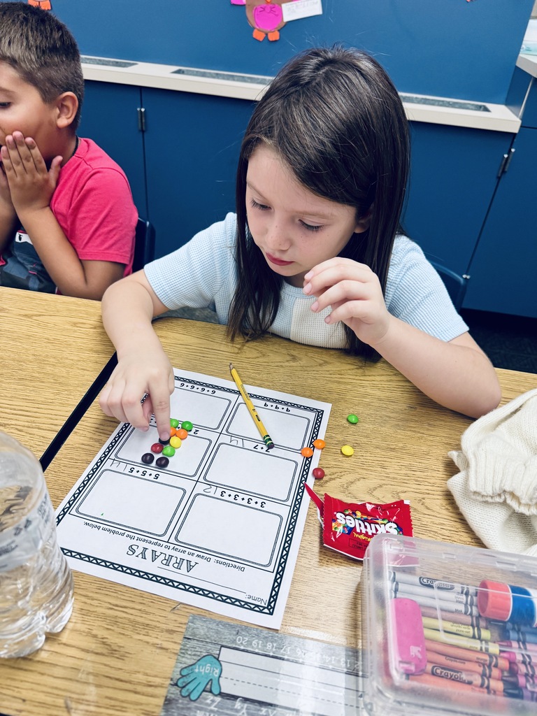 student at desk working with skittles and math arrays