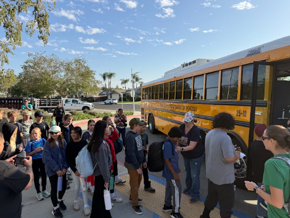 students gathered outside a bus getting ready to leave for camp