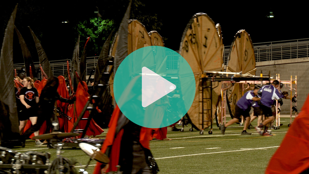 Image of band roadies pushing props onto a football field