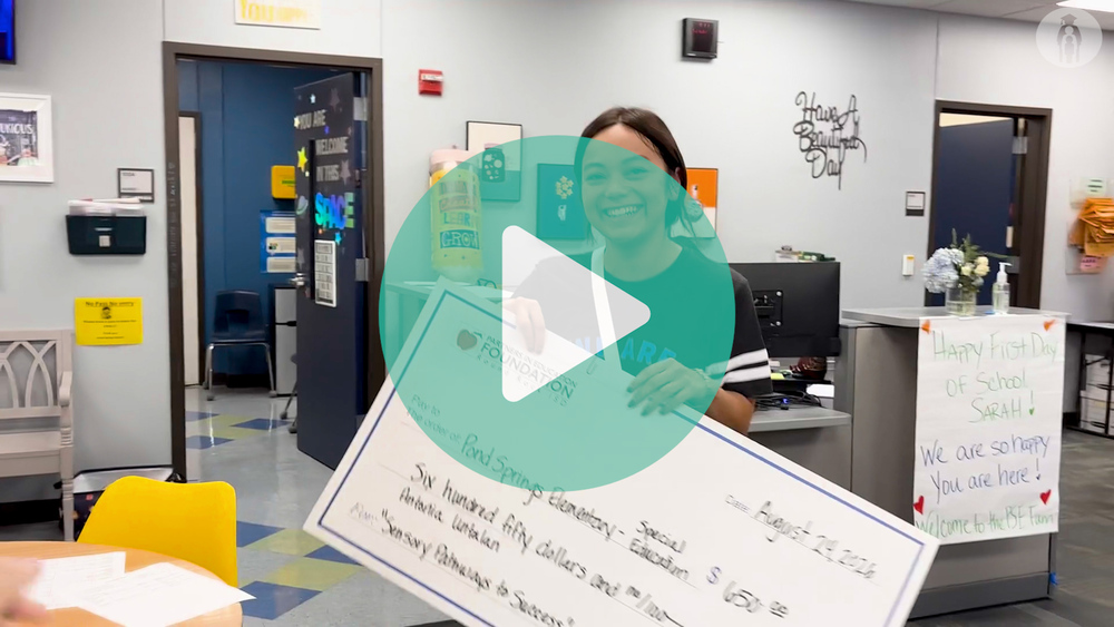 Teacher smiling as she recieves big check from PIEF