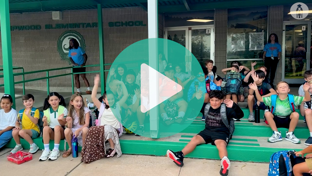student at Deep wood elementary sitting on front steps cheering and waving.