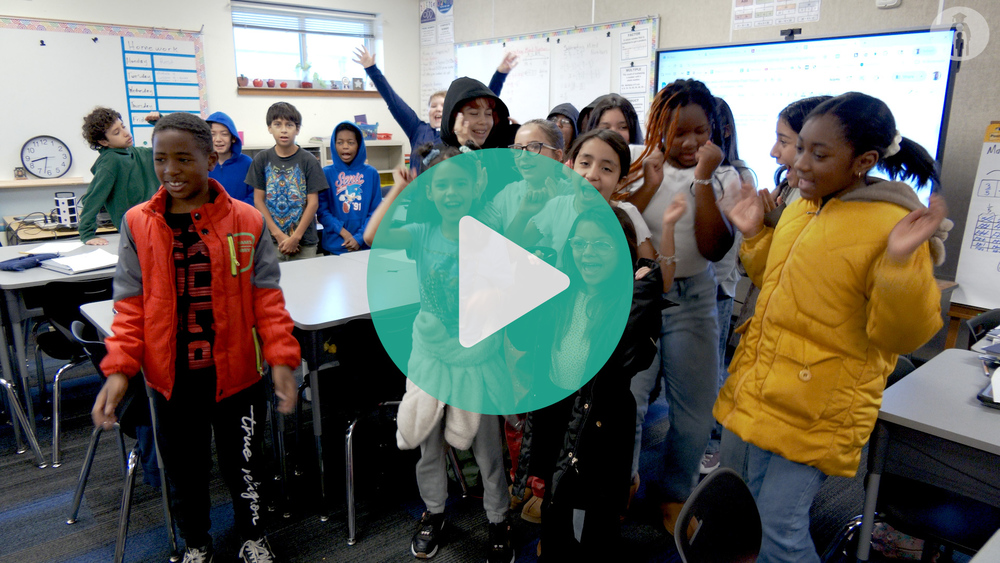 Students cheering in front of the camera in a classroom.