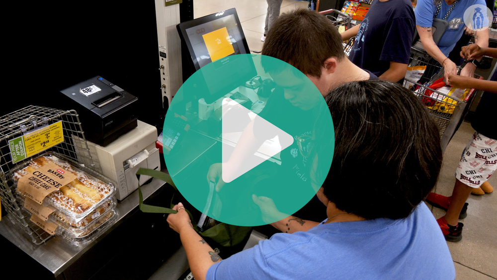 Image of FCC student and teacher ringing up a bag of cheese at HEB self checkout register.