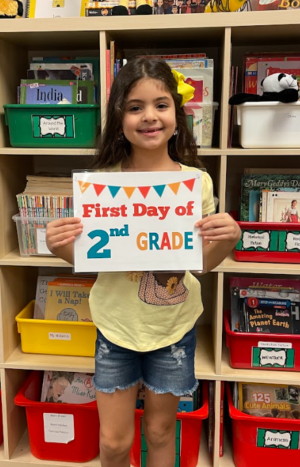 Student holding up a first day of 2nd grade sign