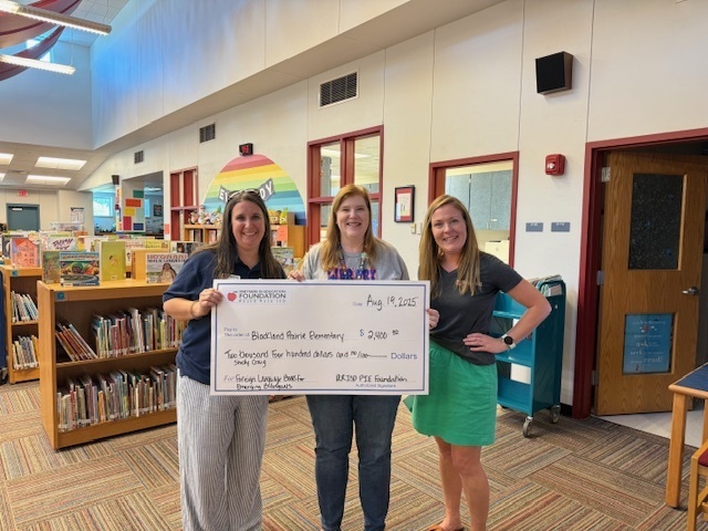 3 adults holding a check