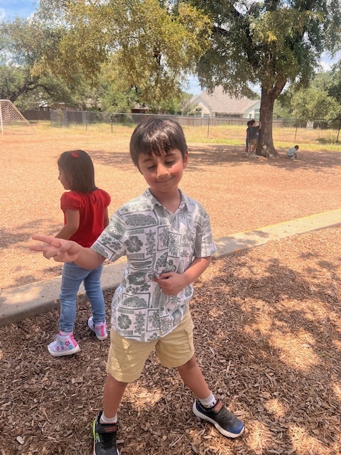 Kinder student outside at recess giving the peace sign