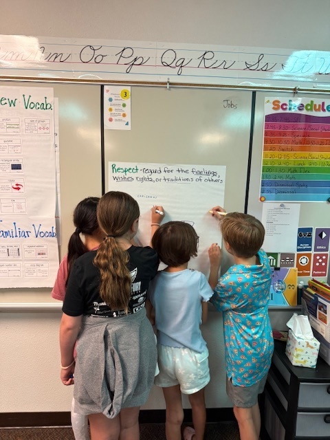 4 students writing on a chart about respect