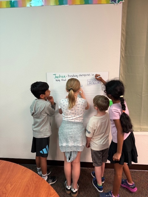 4 students writing on a chart about justice