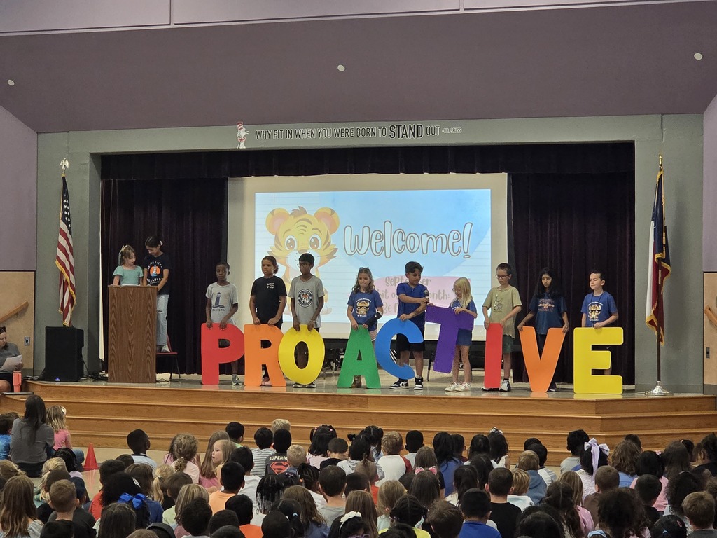 Students on stage holding a sign that says "Proactive"