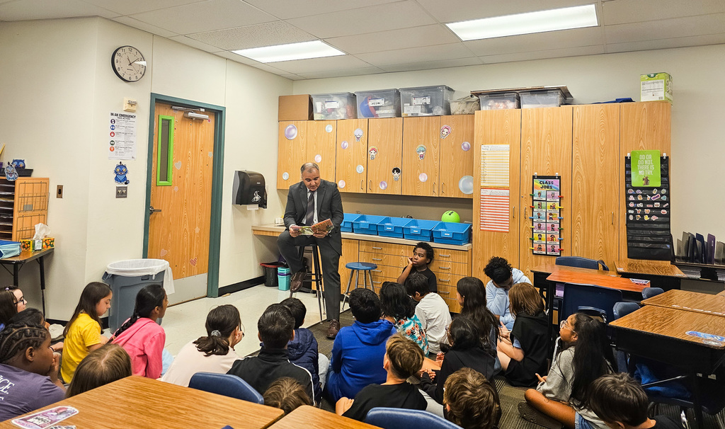 Staff and volunteers reading math books to young students at Jollyville Elementary School