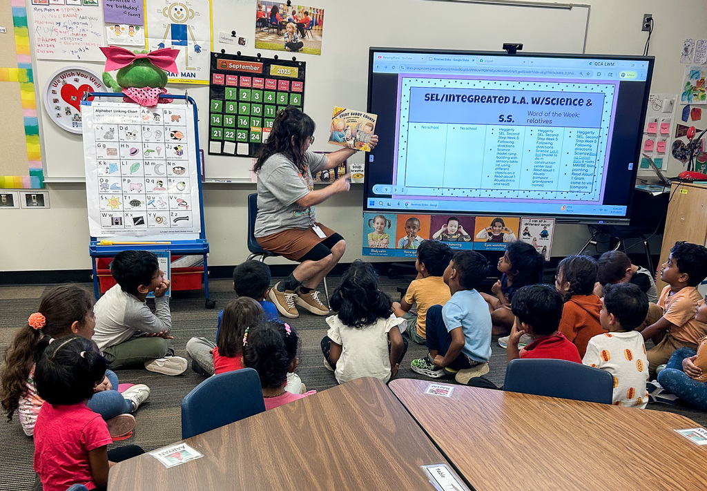 Staff and volunteers reading math books to young students at Jollyville Elementary School