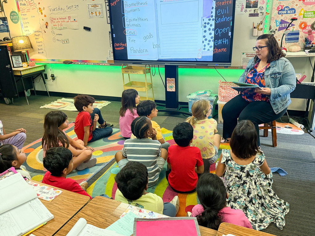 Staff and volunteers reading math books to young students at Jollyville Elementary School