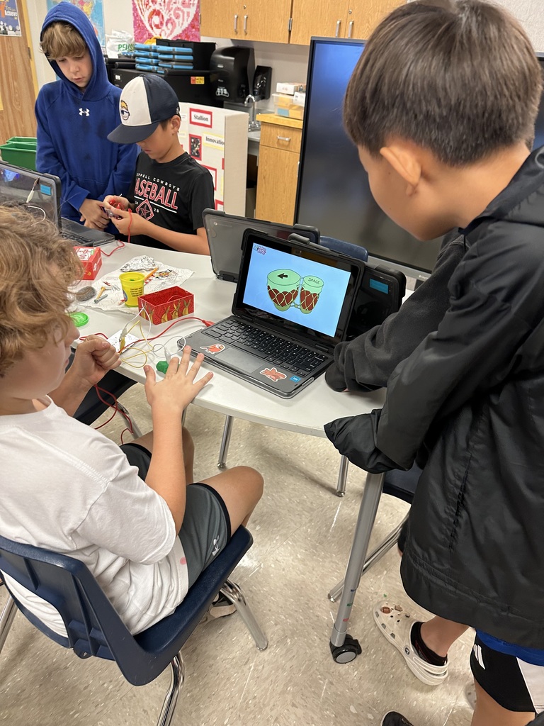 Two students playing the online bongos from makey makey.